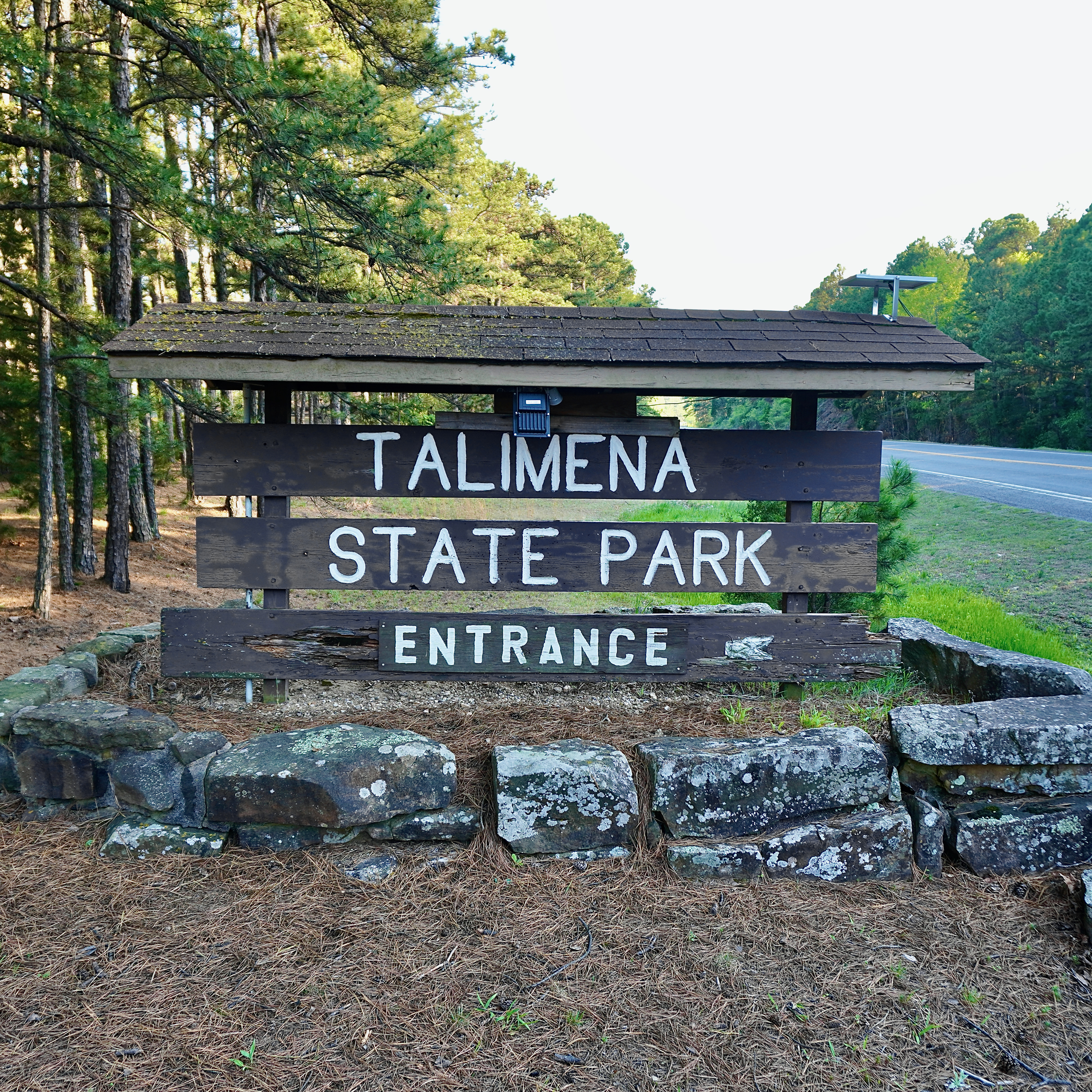 a wooden sign in a forest that says talimena state park