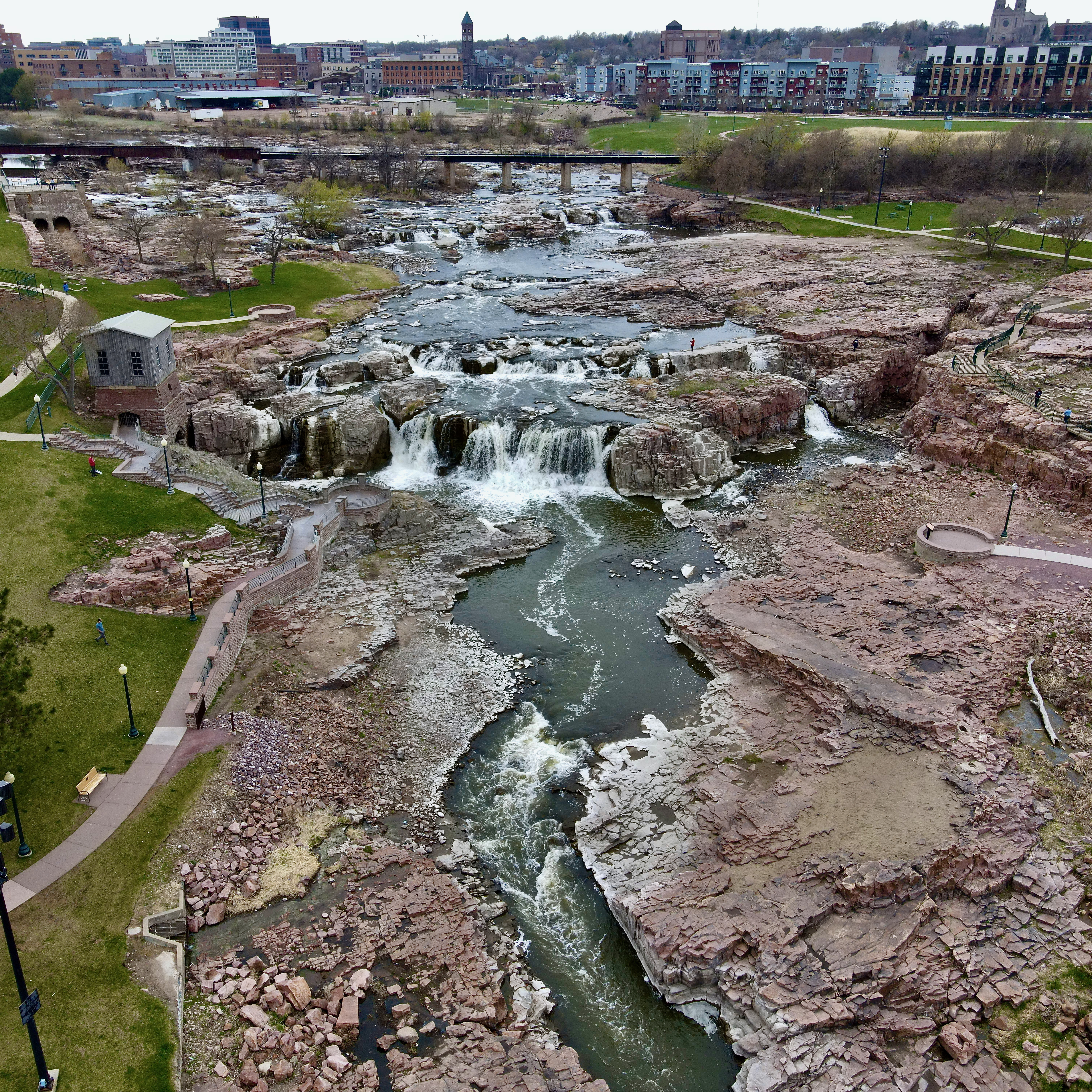 a high drone shot of sioux falls in south dakota with water flowing through rocks