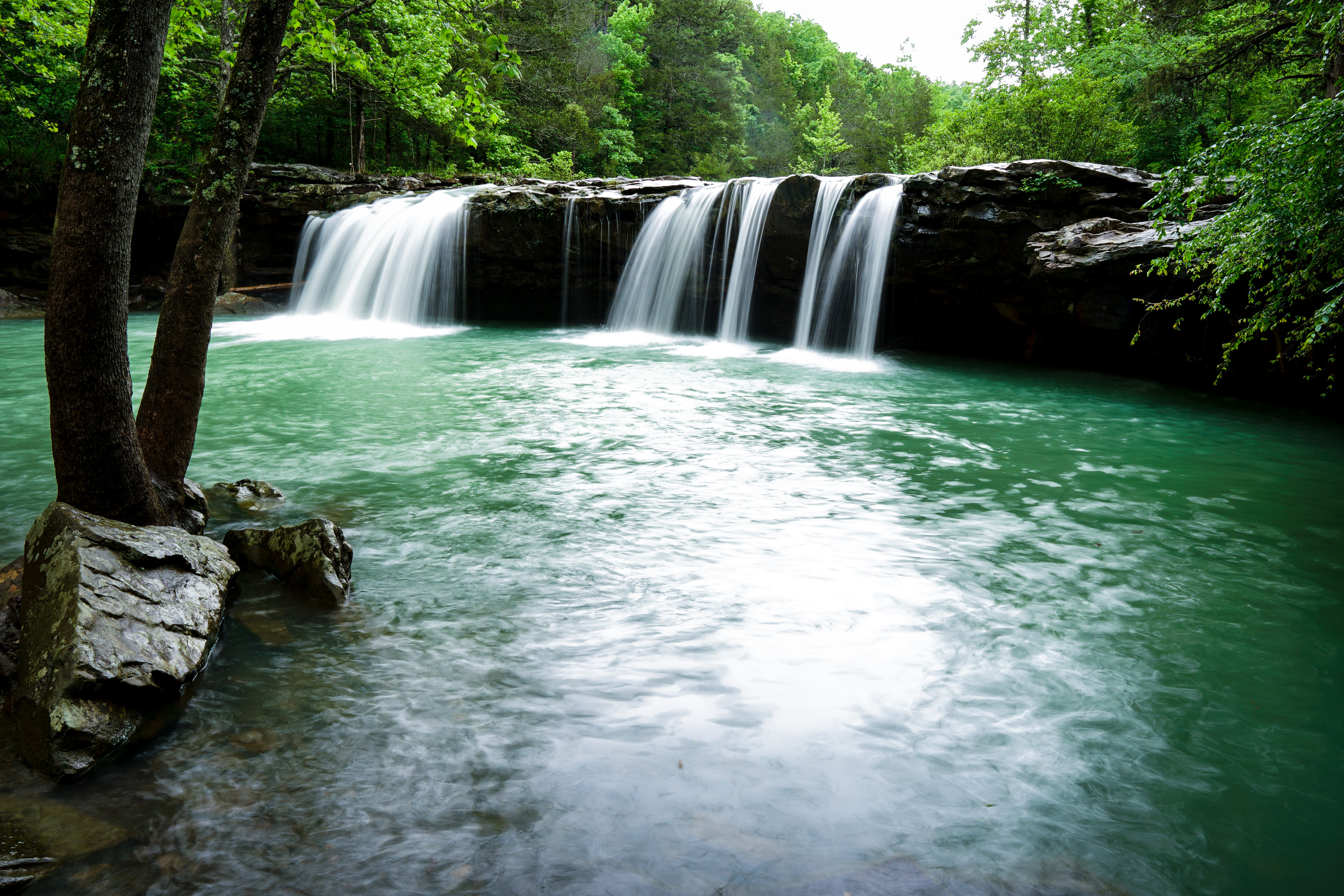 a green creek and a waterfall with two sides of falling water