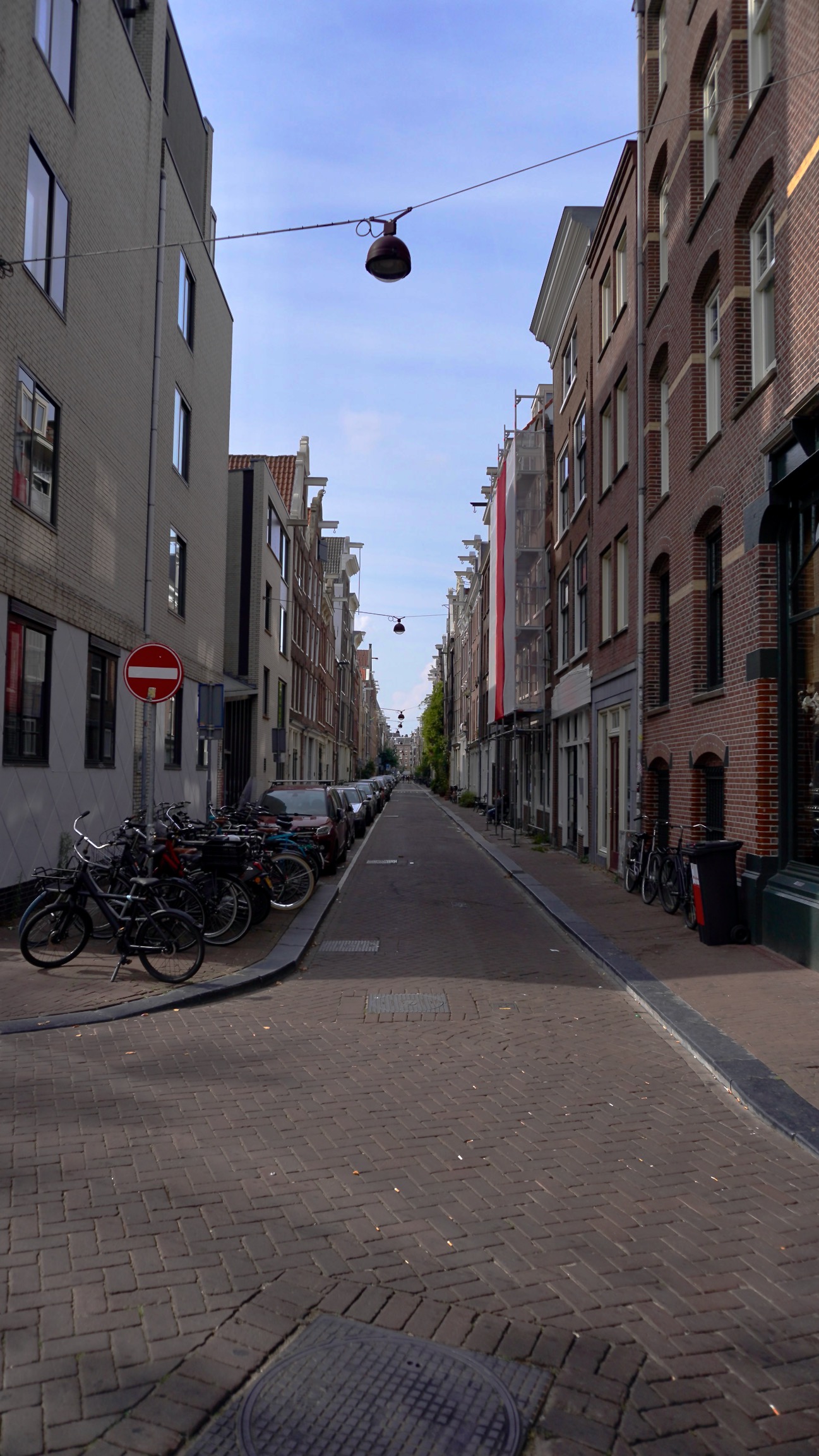 a narrow street with dutch building on each side of a brick street