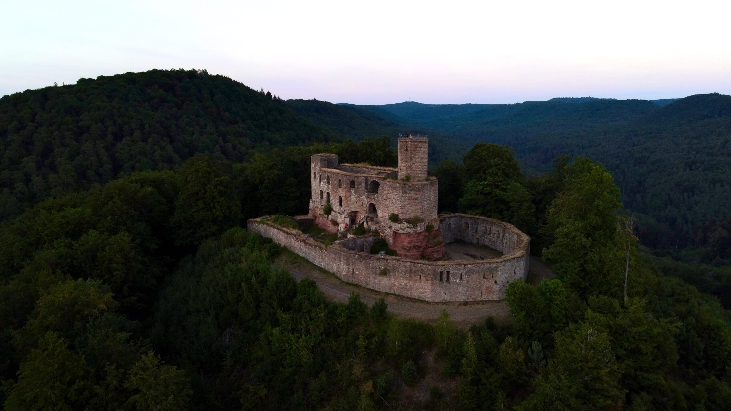 a drone picture of the Gräfenstein Castle with the forest and hills behind it