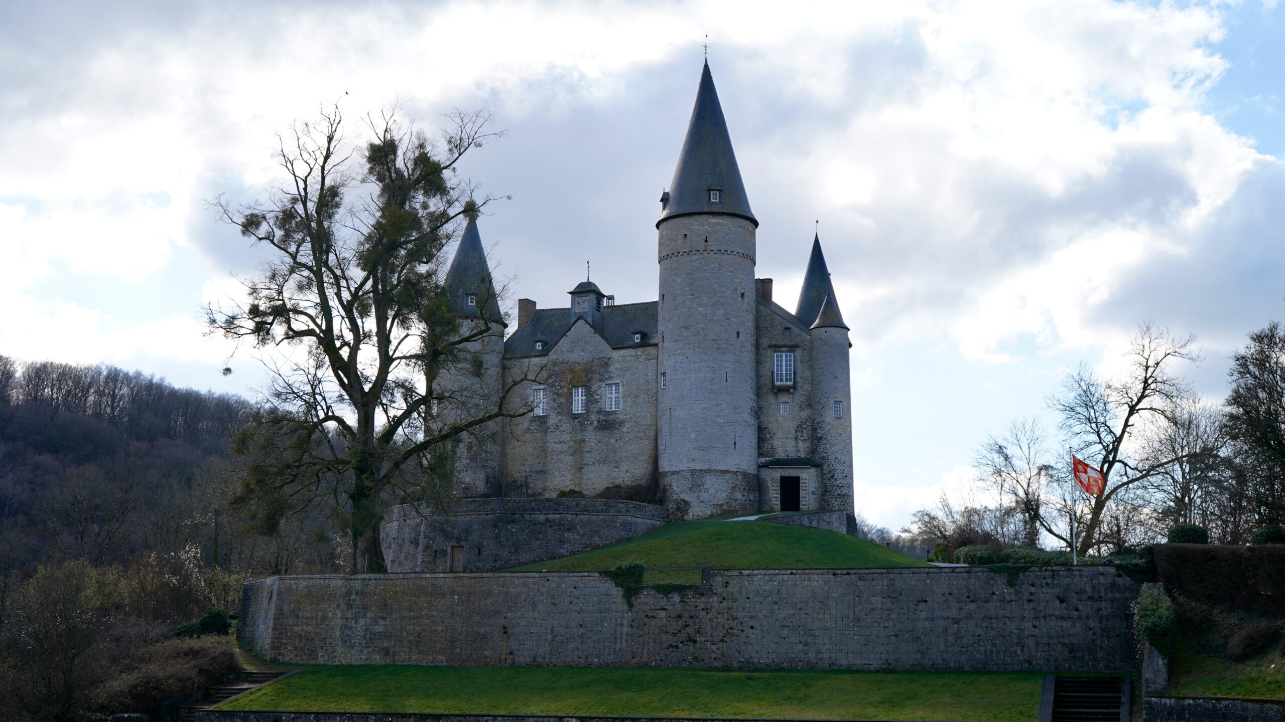 veves castle on a small hill with spires on each side and grey stone