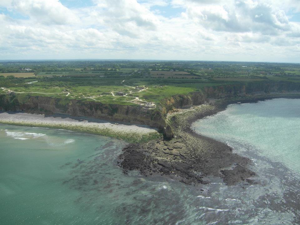 green fields on top of tall cliffs and the ocean in front of pointe du hoc france