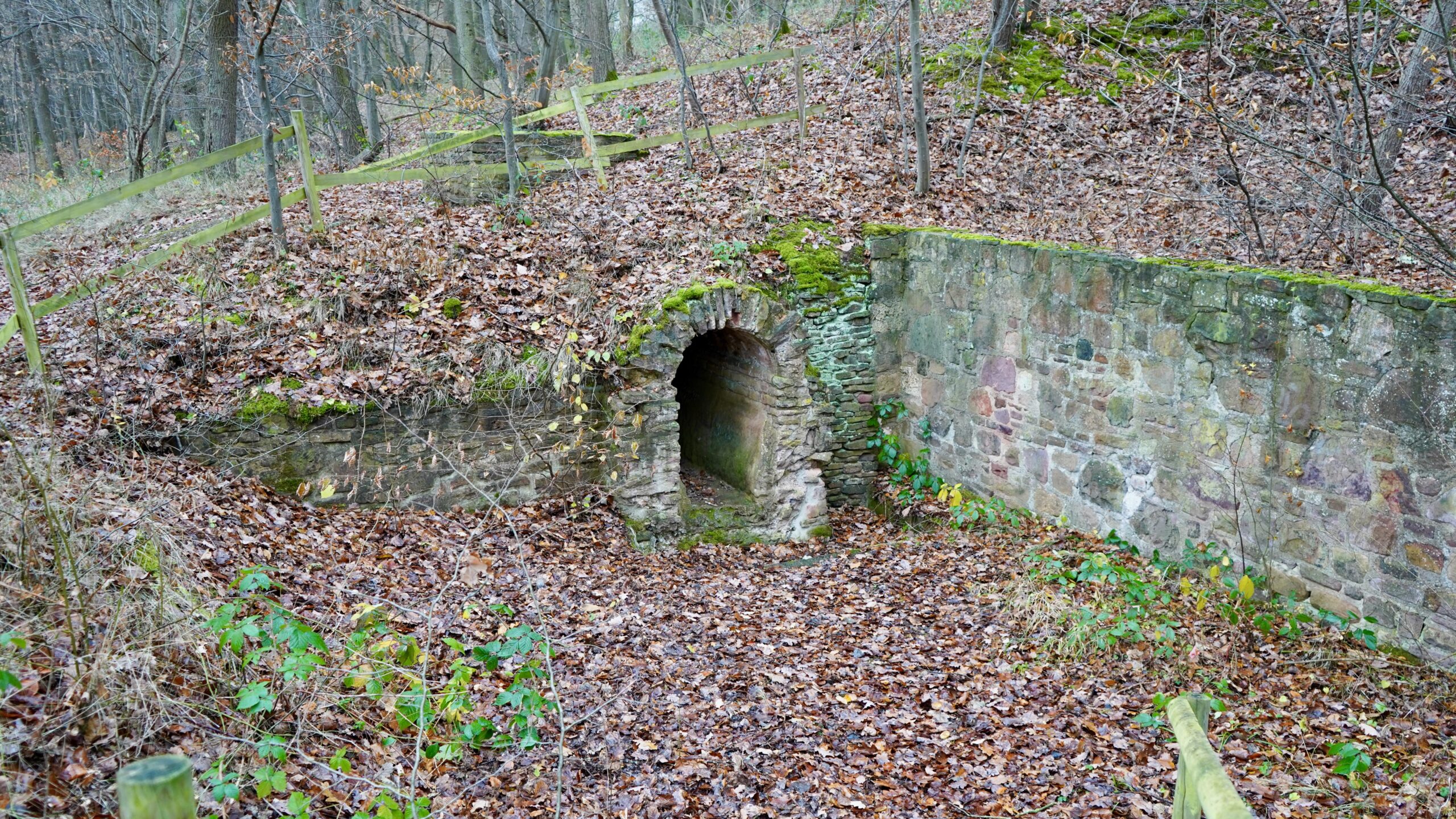 an excavated and exposed roman aqueduct with a stone wall and cross section of stone with a flat bottom, vertical sides, and an arched top about 3 feet tall and 2 feet wide in the eifel region germany