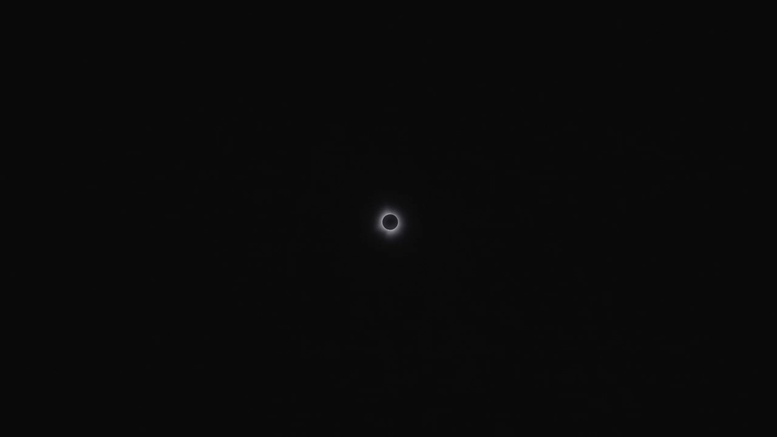 a picture of the 2024 eclipse with a black background, black center, and white corona around the sun and moon