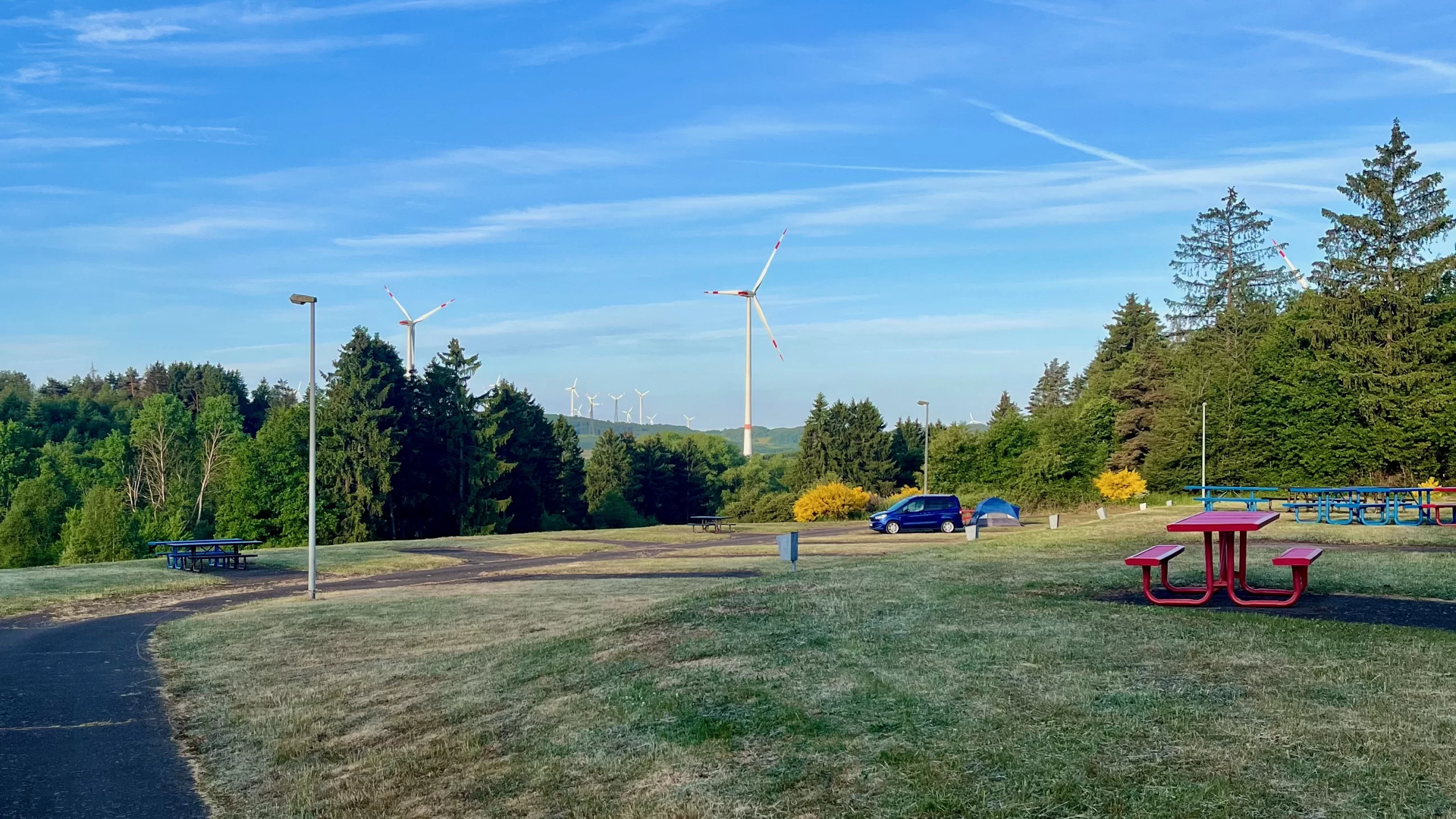 green hills, blue van, and blue skies with a few white windmills in the background of baumholder campground