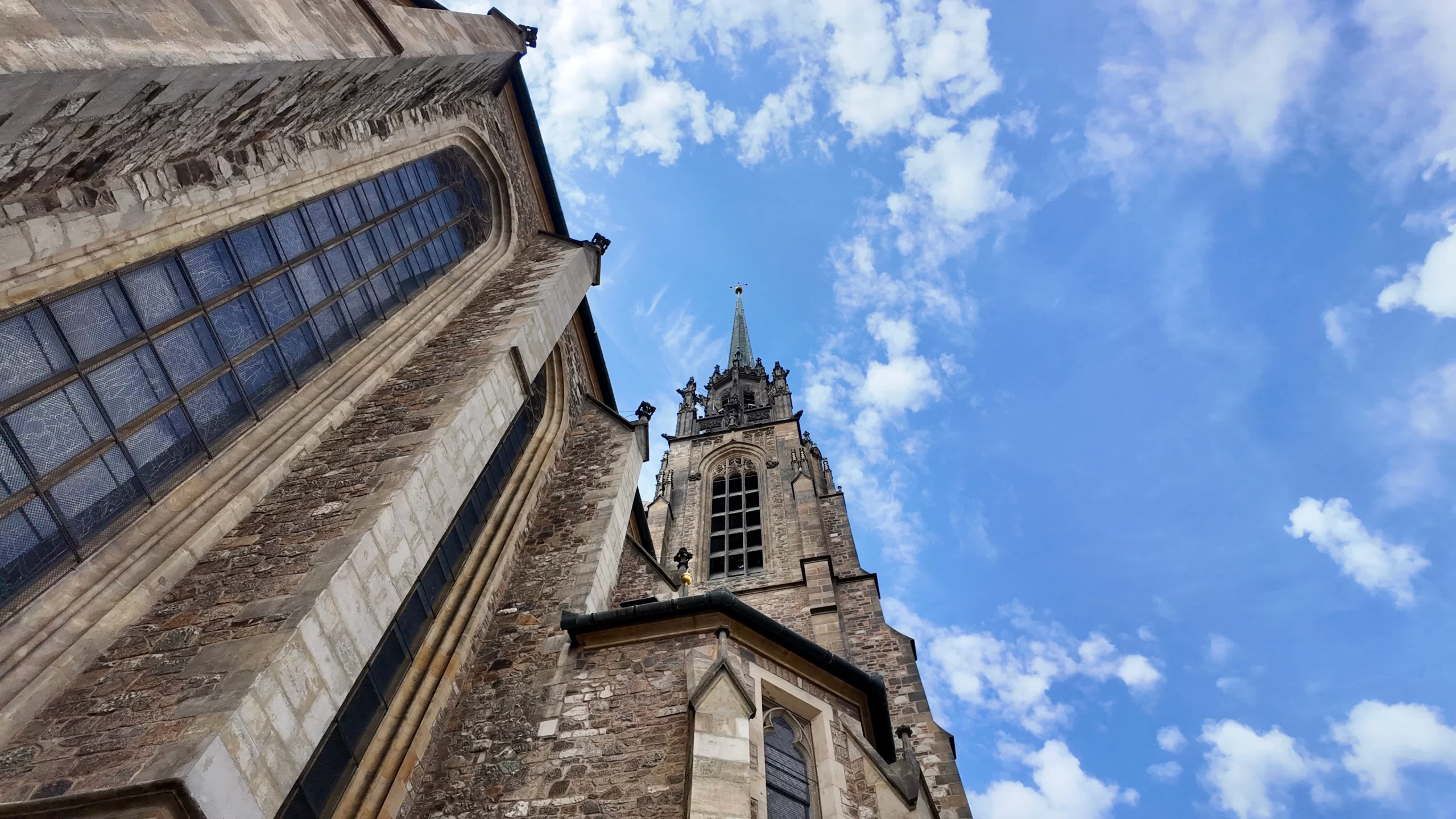 looking up at a blue sky with the grey church on the left
